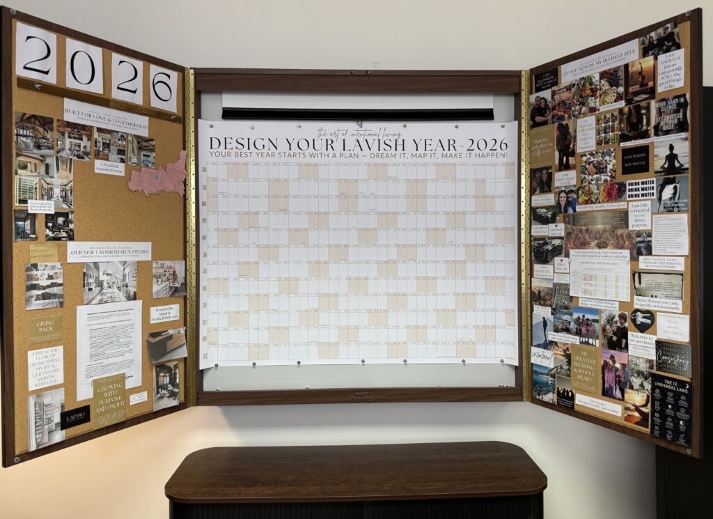 A large 3ft x 4ft 2026 Signature Wall Calendar from Lavish Interiors styled on a wall as a central visual anchor, surrounded by an interior design vision board with photos and inspiration sketches.