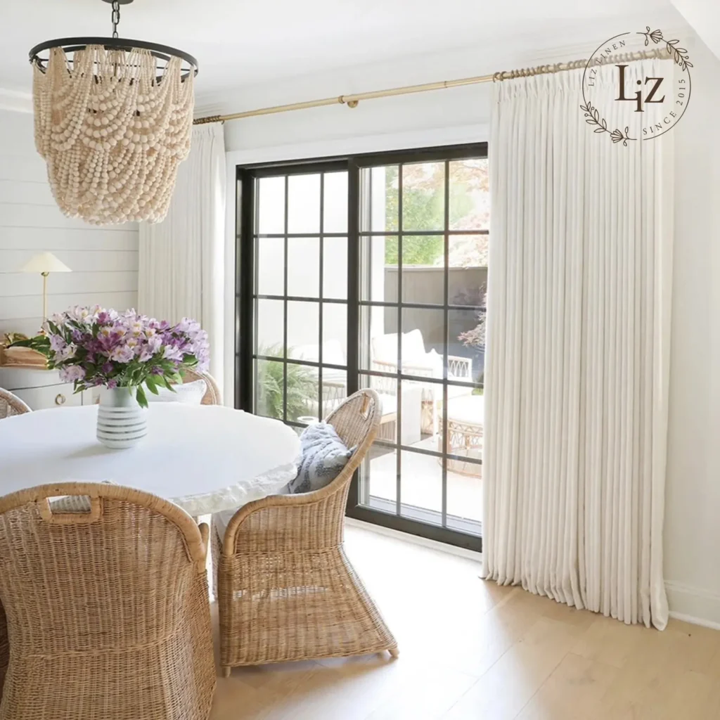 Floor-to-ceiling light airy linen curtains diffusing soft summer sunlight in a coastal-inspired room.