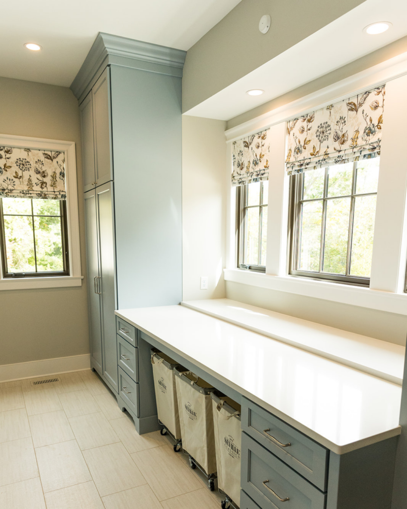 Custom botanical floral Roman shades tailored for a luxury laundry room window treatment by Lavish Interiors.