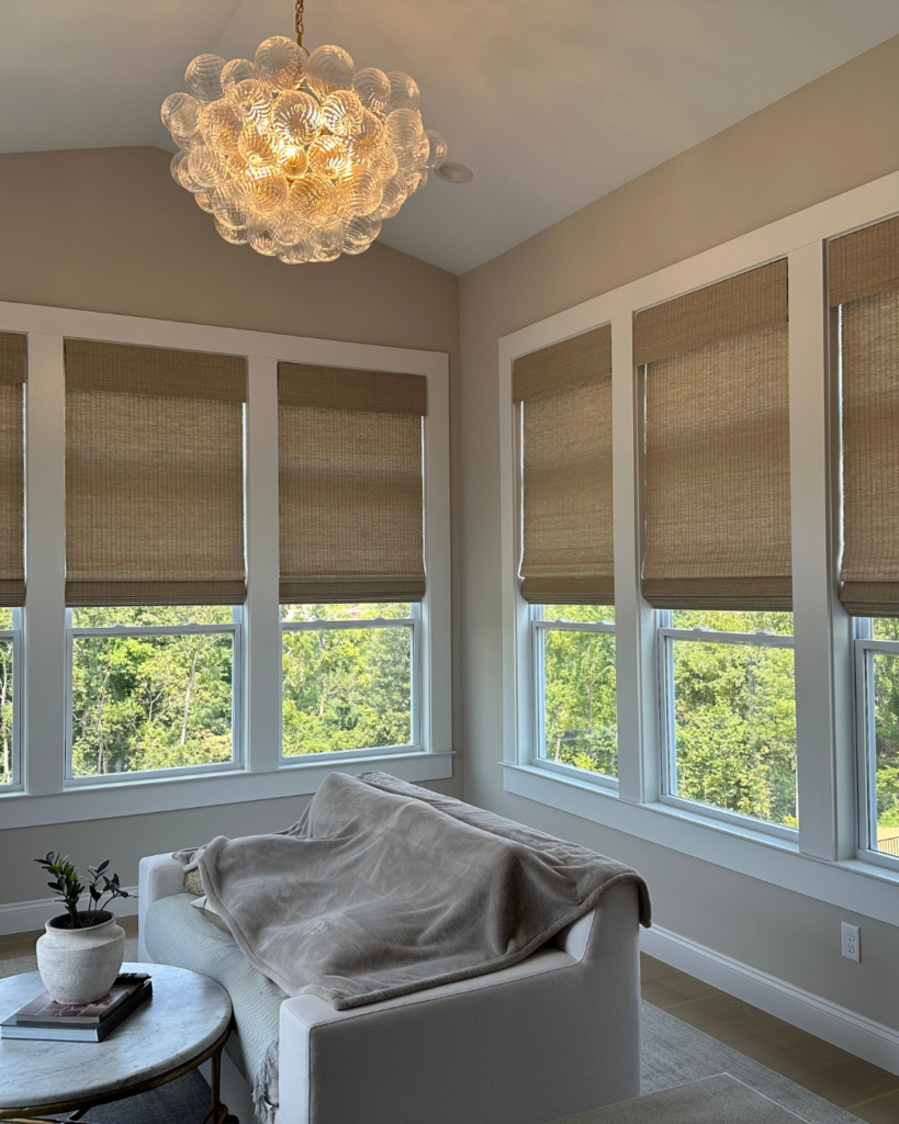 Natural woven wood shades installed on large sunroom windows in a luxury living space by St Louis Blinds and Shutters