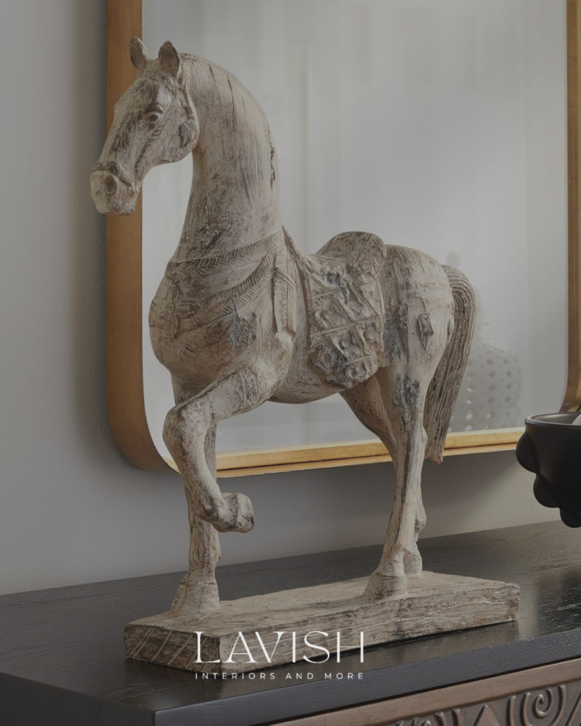 Rustic distressed ceramic horse sculpture on a moody modern console table under a gold mirror.