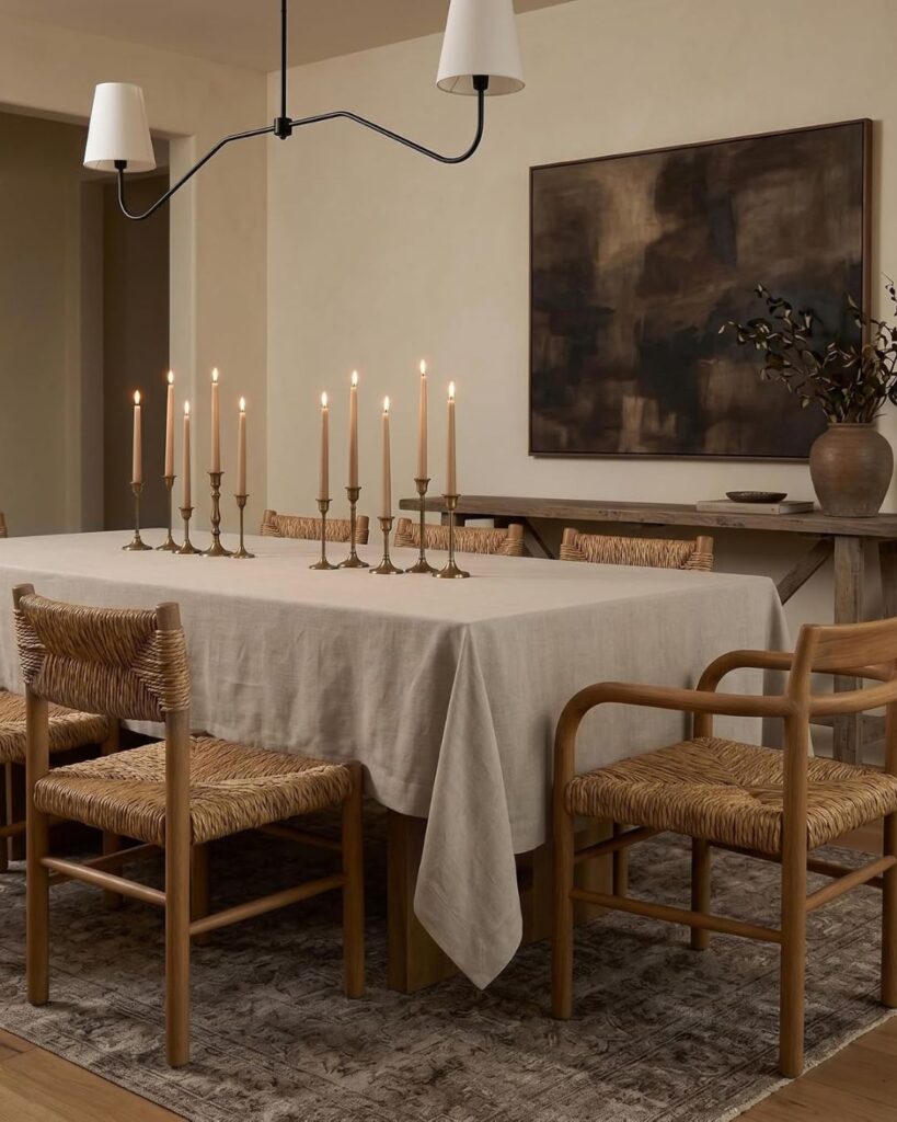 Warm, neutral dining room designed for gathering with a wooden table, layered textiles, and soft ambient lighting.